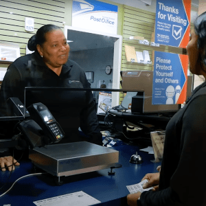 Staff member from Mail & Package Services helps customer at the front counter in lower Prospector on the UNC Charlotte campus