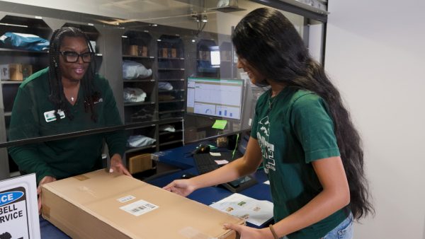 mail services employee hands package to student over the mail package counter