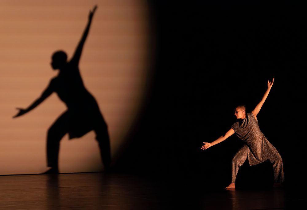 Student dancing on stage with reflection on the curtain