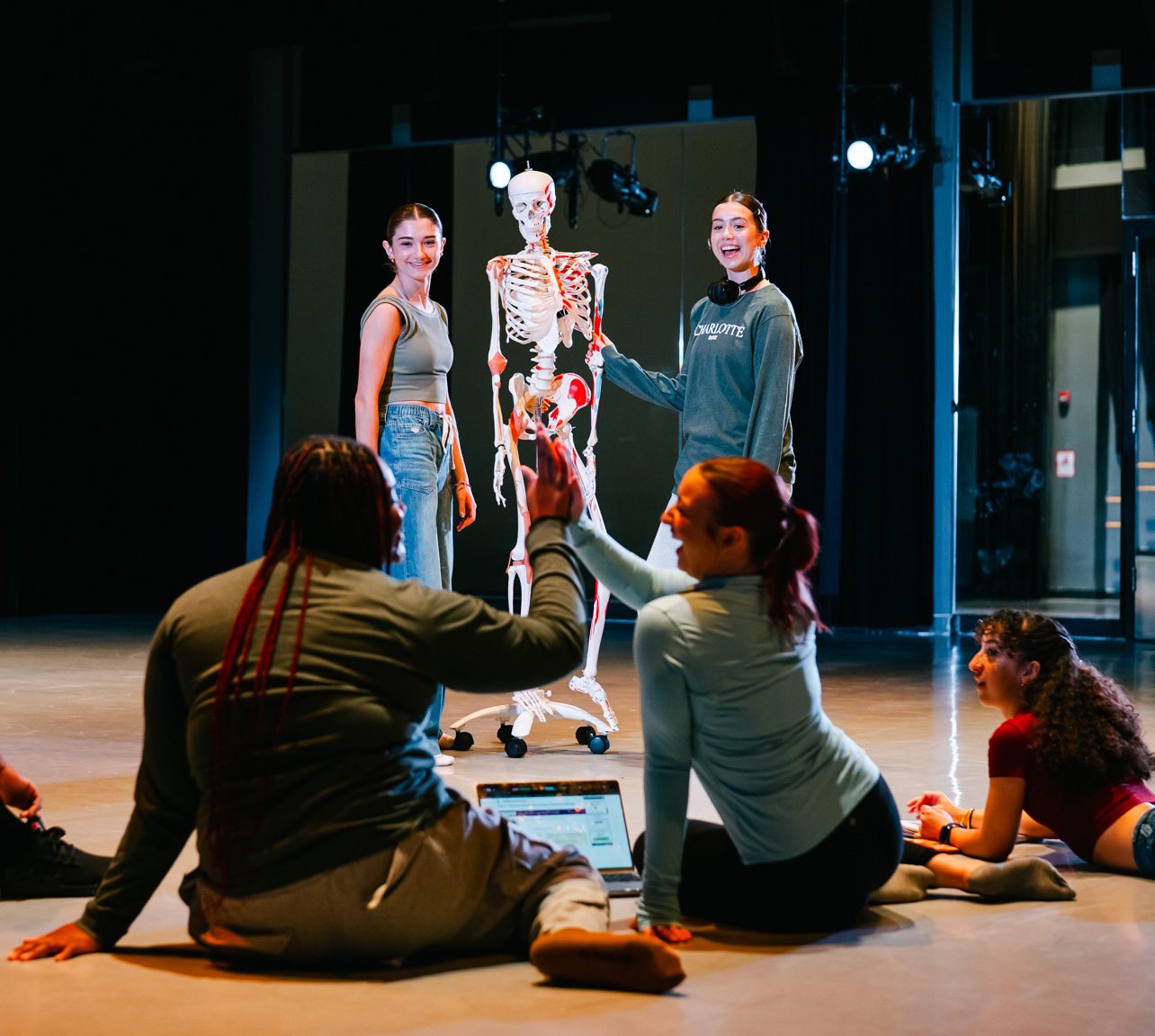 students with skeleton in the dance studio talking about anatomy 