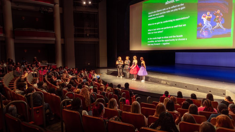 Students on stage presenting with screen behind them