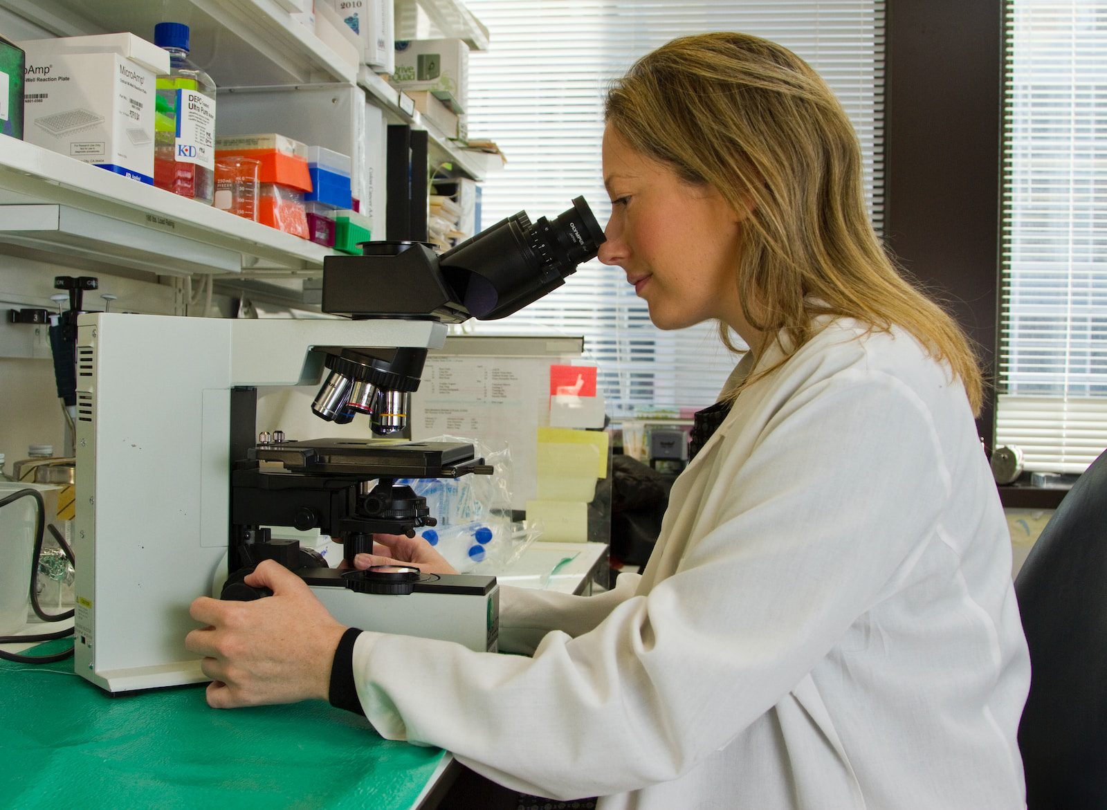 woman in white coat holding black dslr camera